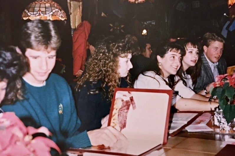 Group of late 80s university students at restaurant table looking at menu