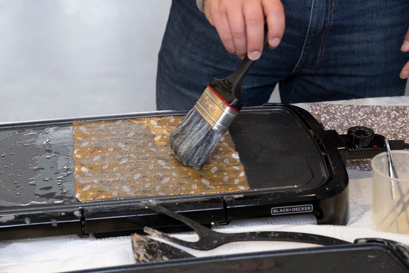 Class of of person spreading wax on a piece of fabric on a griddle. 
