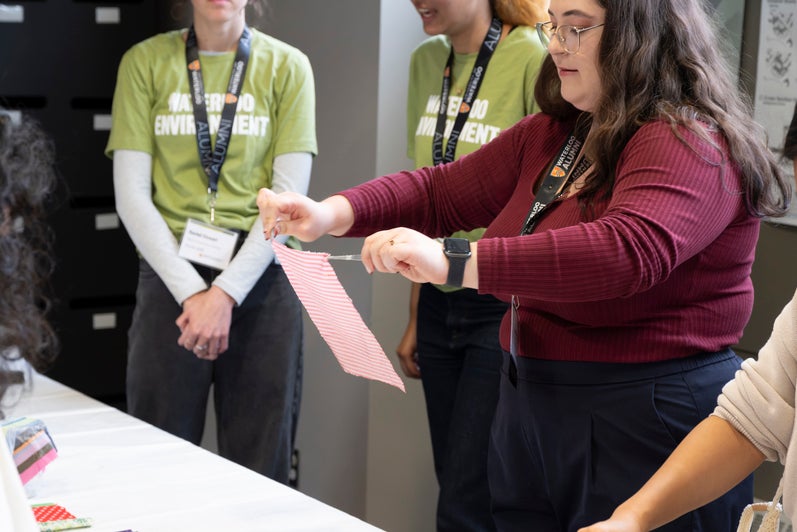 A group of people participating in an activity at a workshop, with one person demonstrating a task while others observe.