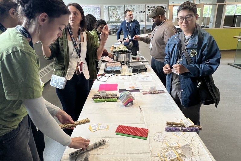 A group of people line both sides of a long table with a craft activity. 
