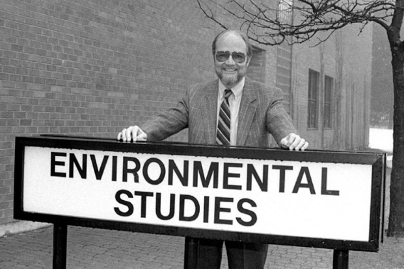 Black and white image of man in from of Environmental Students sign