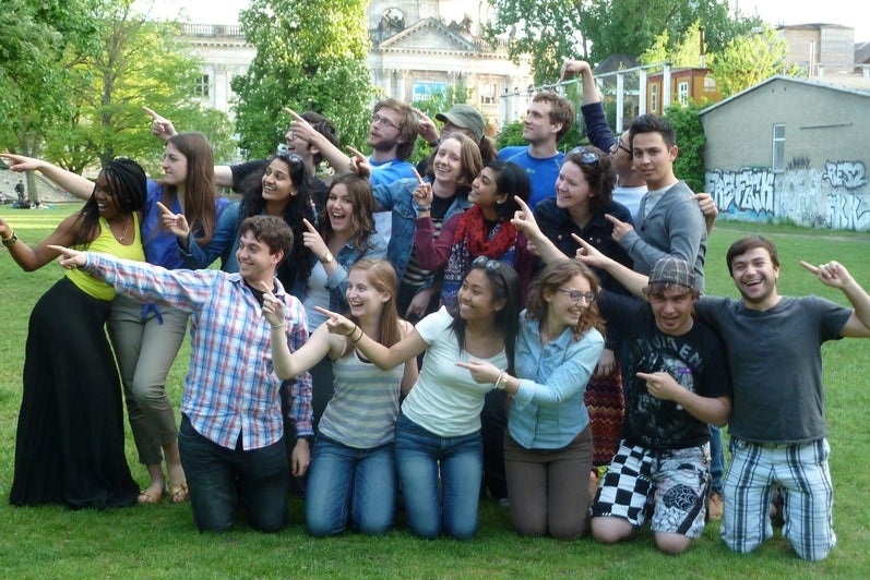 Group of university students in a park smiling and pointing off into the distance