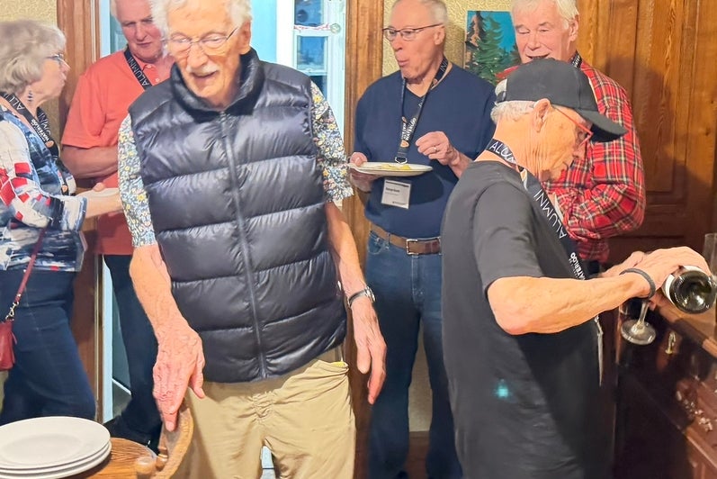 A group of older adults is gathered in a kitchenat a party with a warm, inviting atmosphere.