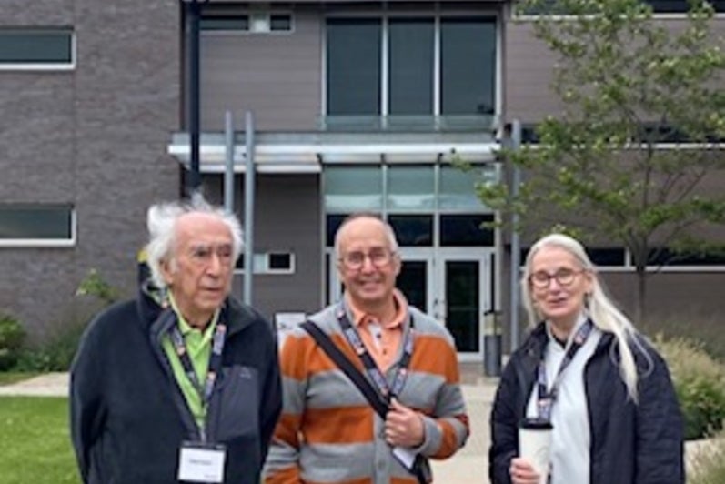 Three individuals standing outside a modern building.