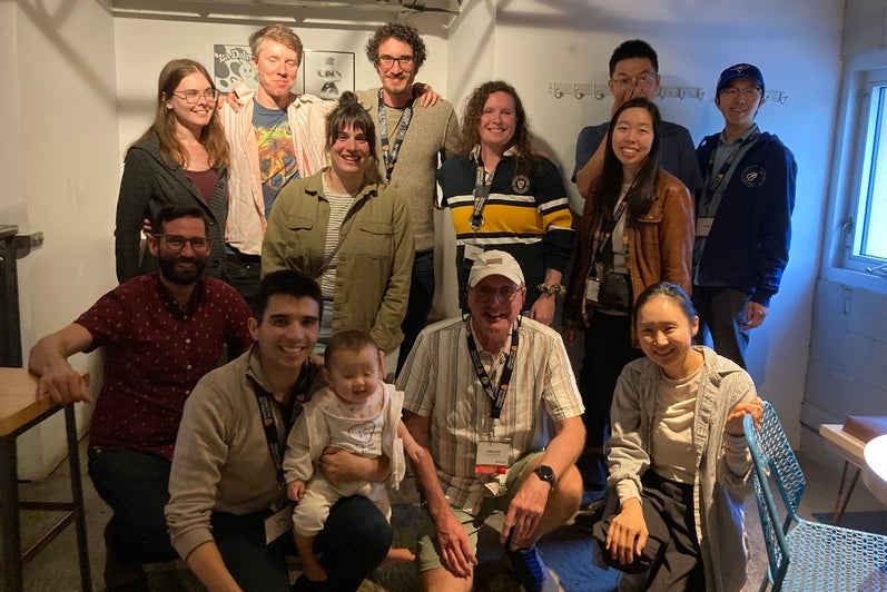 A group of 11 people lined in rows smiling. 