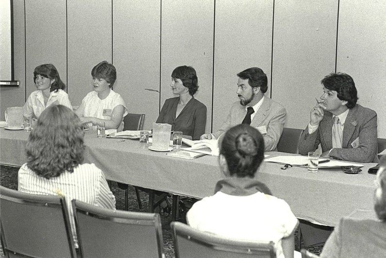 A group of students sitting on one side of a long table, in front of an audience.