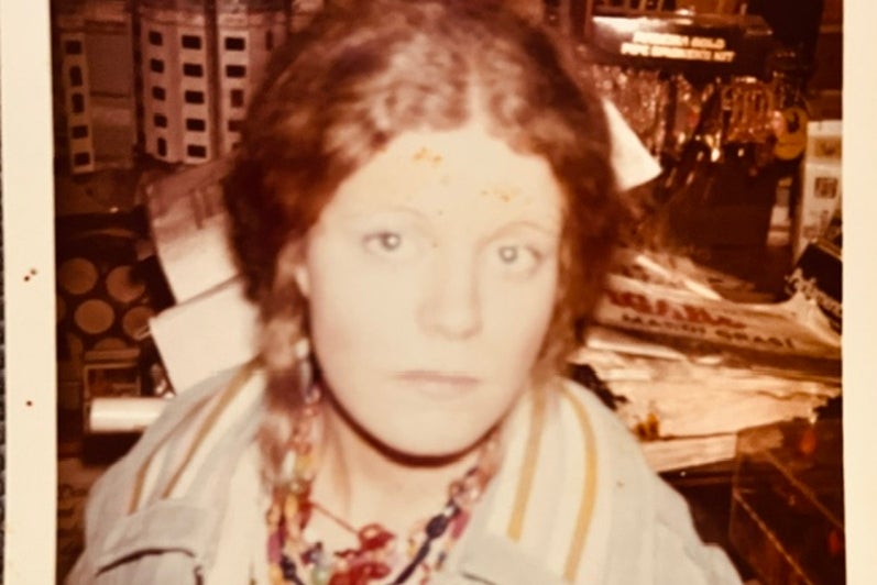Woman with red braids and layered necklaces in sepia toned photograph.