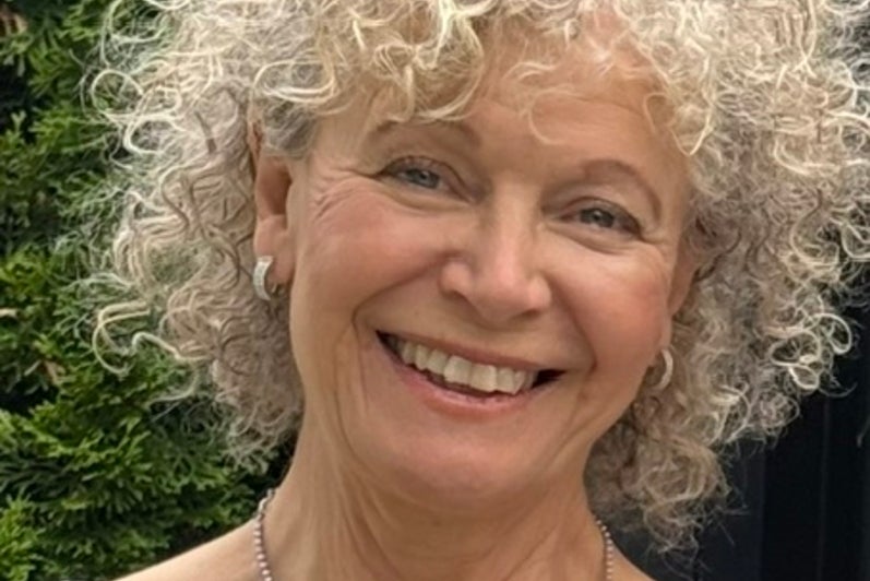 Woman with short, curly blonde hair smiles.