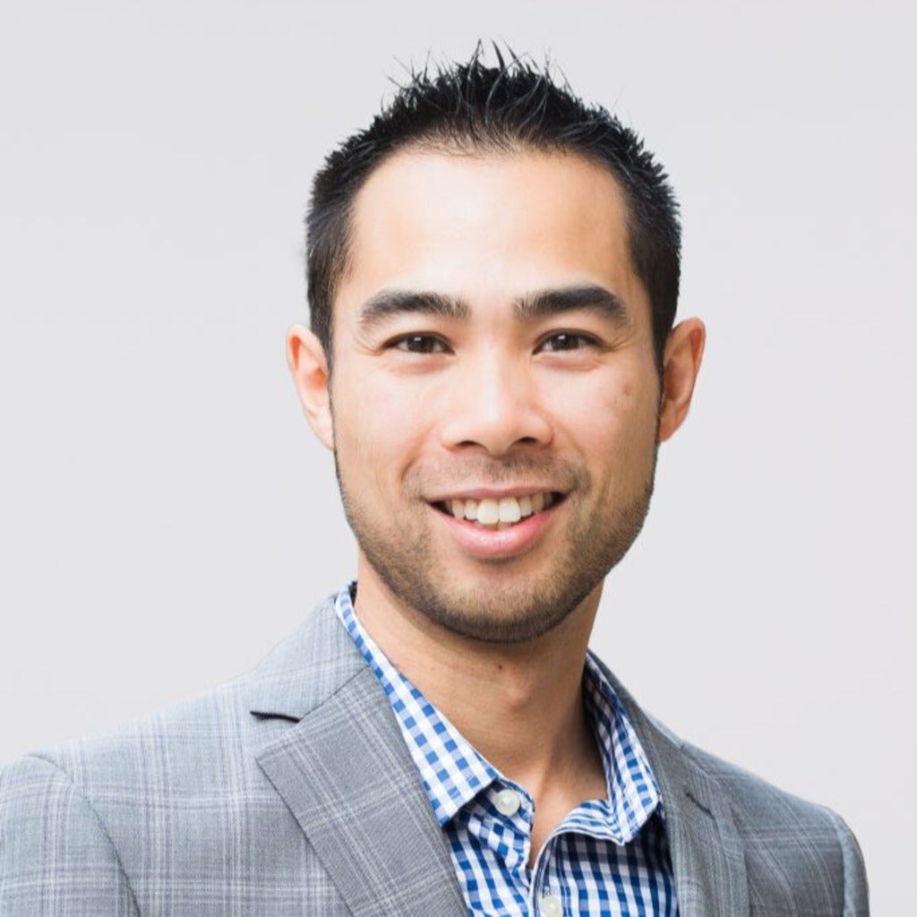 man in collared shirt and suit smiling at viewer