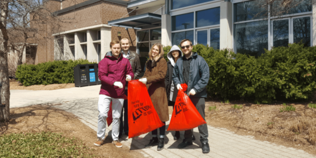 Small group of people holding trash bags for campus clean-up.