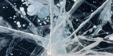 Cracks and bubbles in a section of frozen lake.