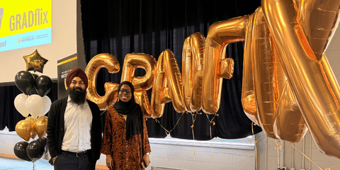 Bashirah and Gurpreet smiling in front of "GRADflix" balloons.