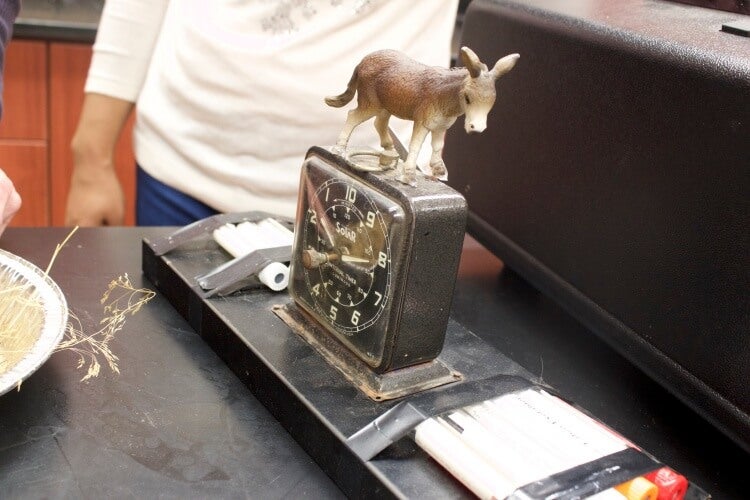 Donkey figurine on top of rusty antique clock