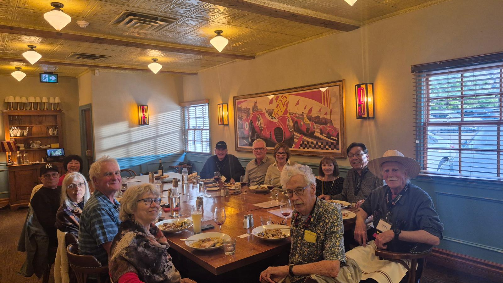 A group of people sitting around a large dining table in a restaurant, sharing a meal and engaging in conversation