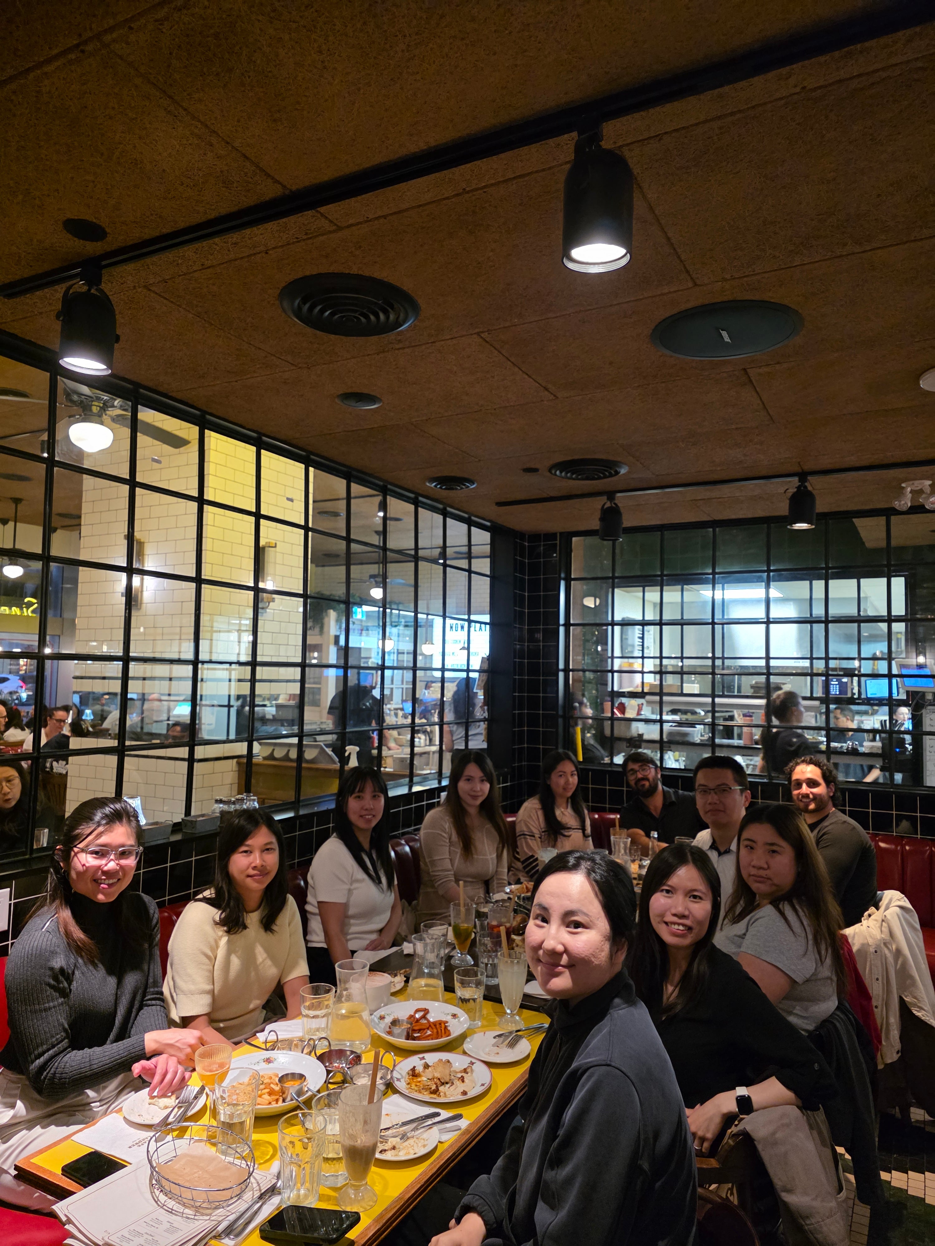 A diverse group of people sitting at a restaurant table, smiling. 