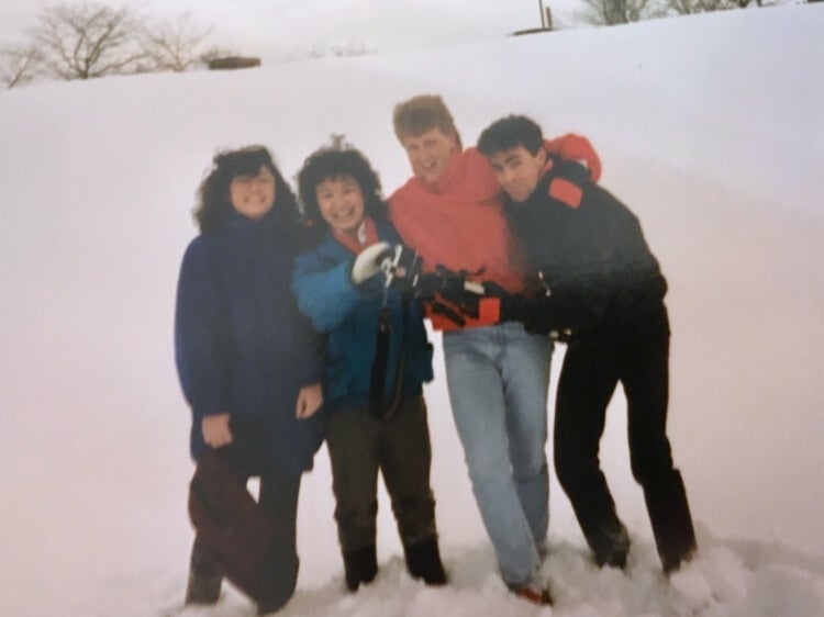 Four university students in the 80s standing in the snow