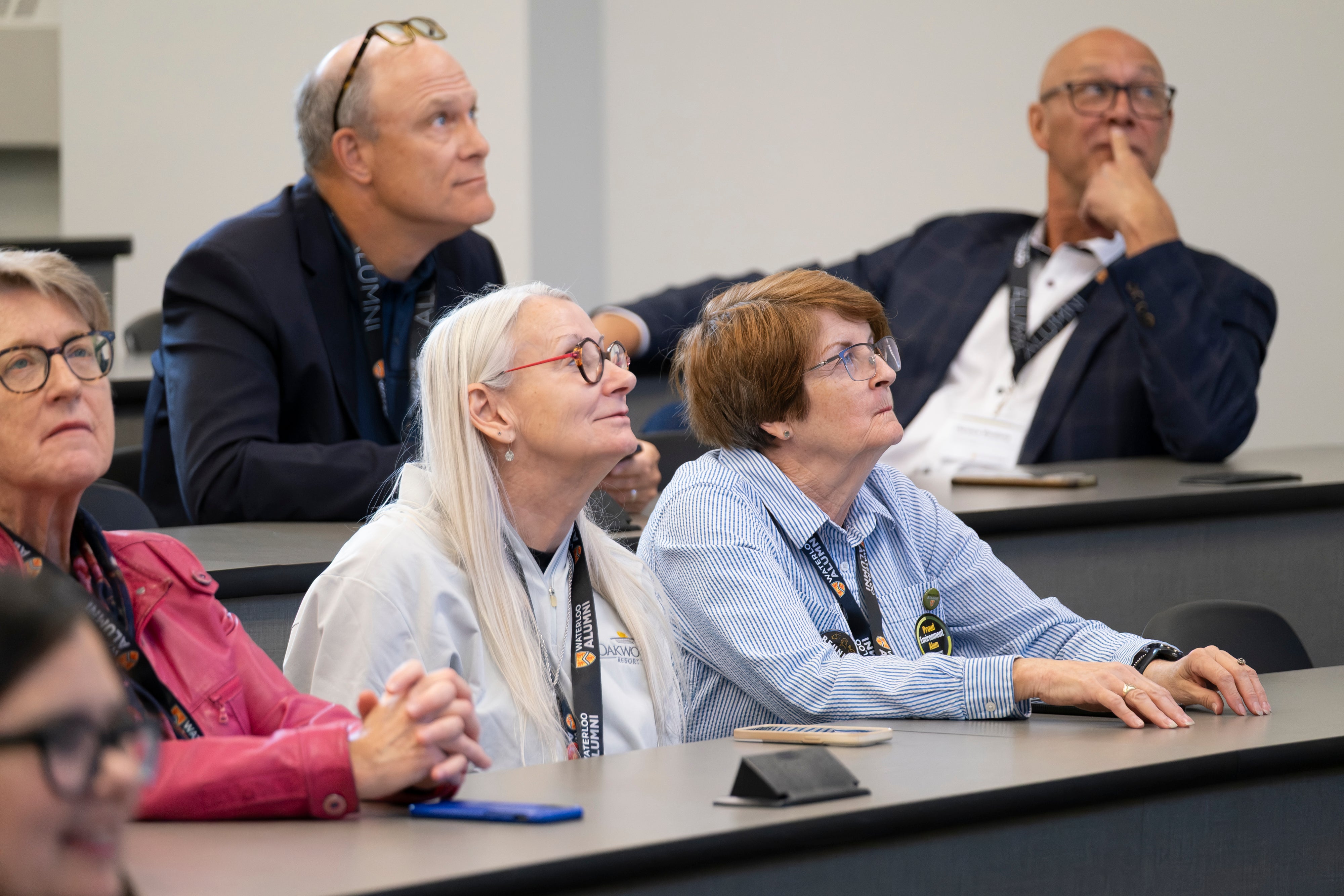 A group of people sitting in a classroom or lecture hall, listening attentively.