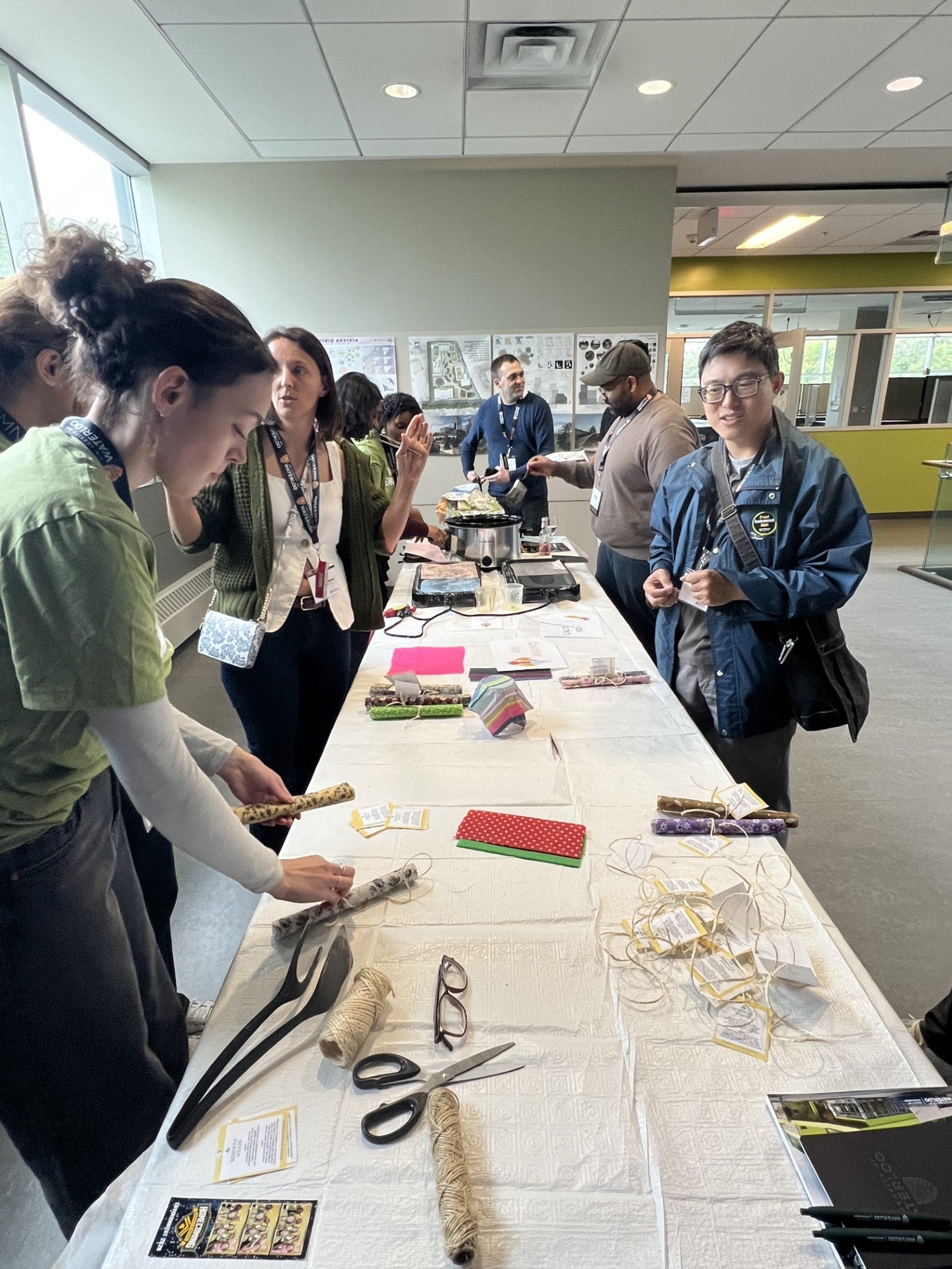 A group of people line both sides of a long table with a craft activity. 