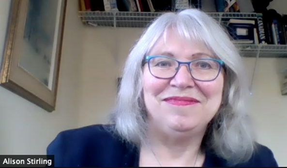 Woman with shoulder length grey hair and glasses smiles.