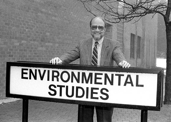 Black and white image of man in from of Environmental Students sign