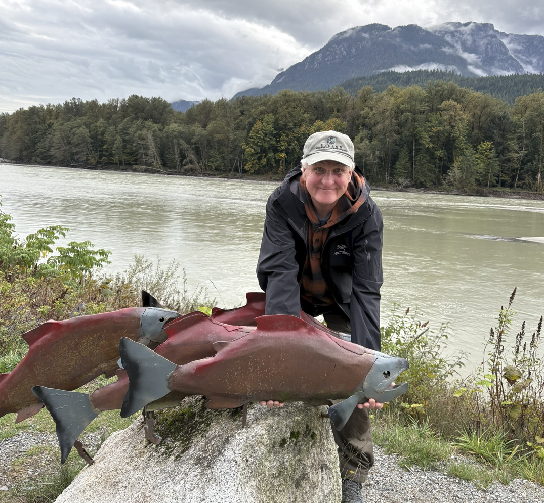 Man with salmon statue by river