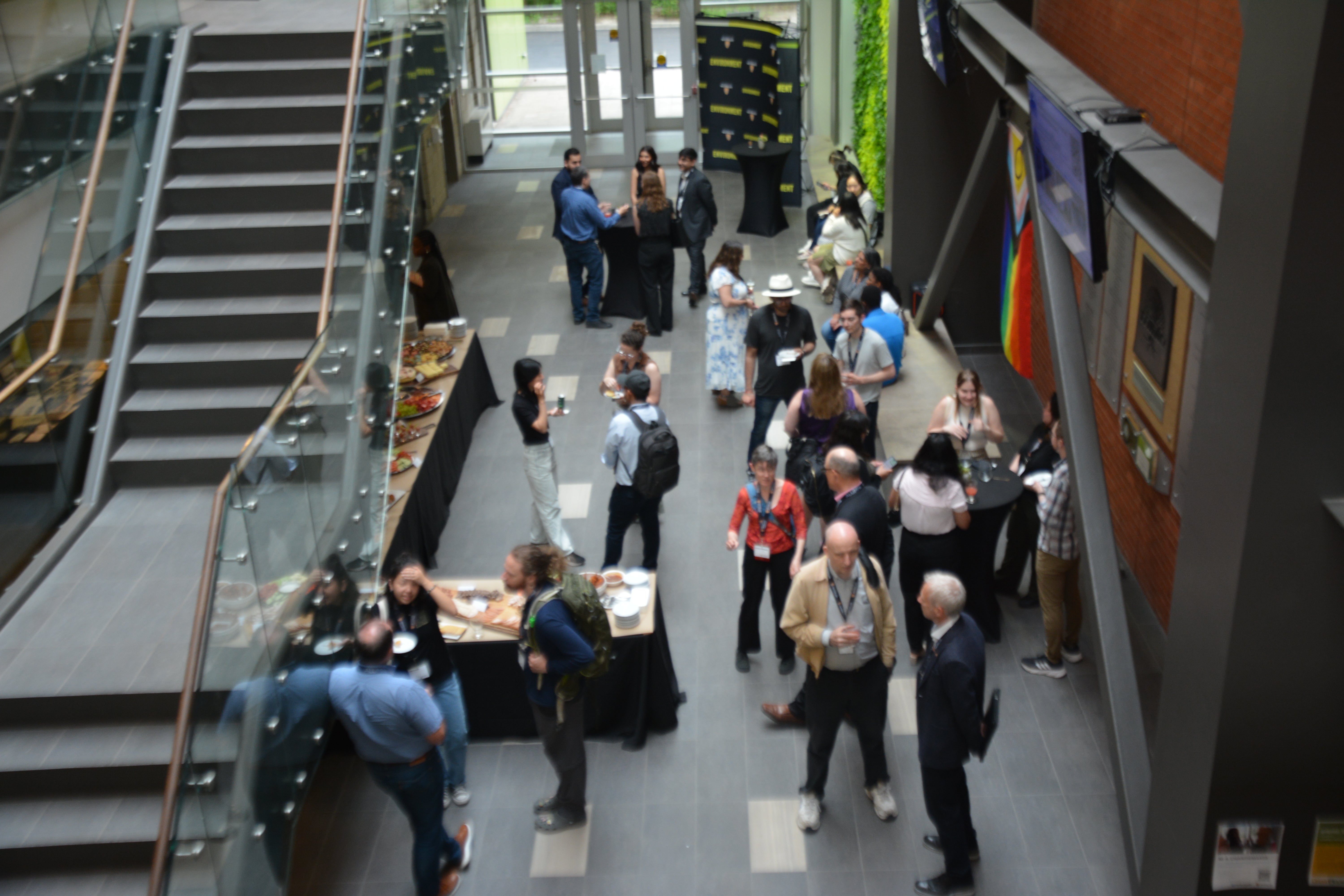 people socializing in an open atrium beside a staircase