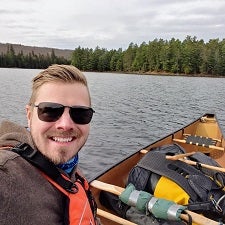 Dustin Carey smiling for a photo in a canoe