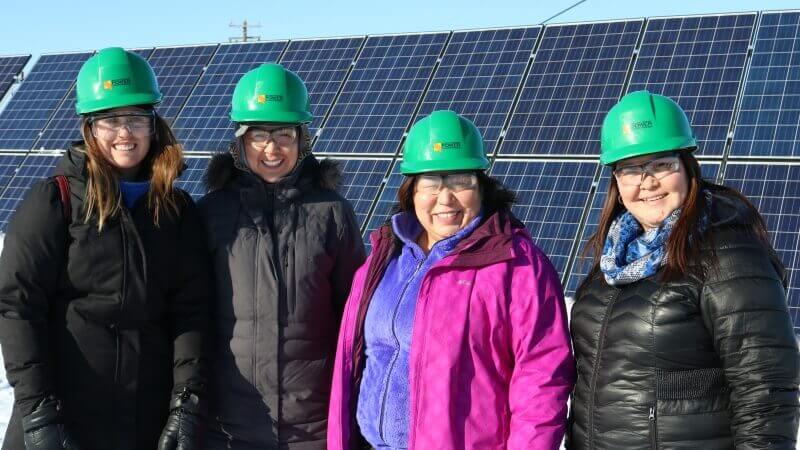 Four women in front of a solar panel