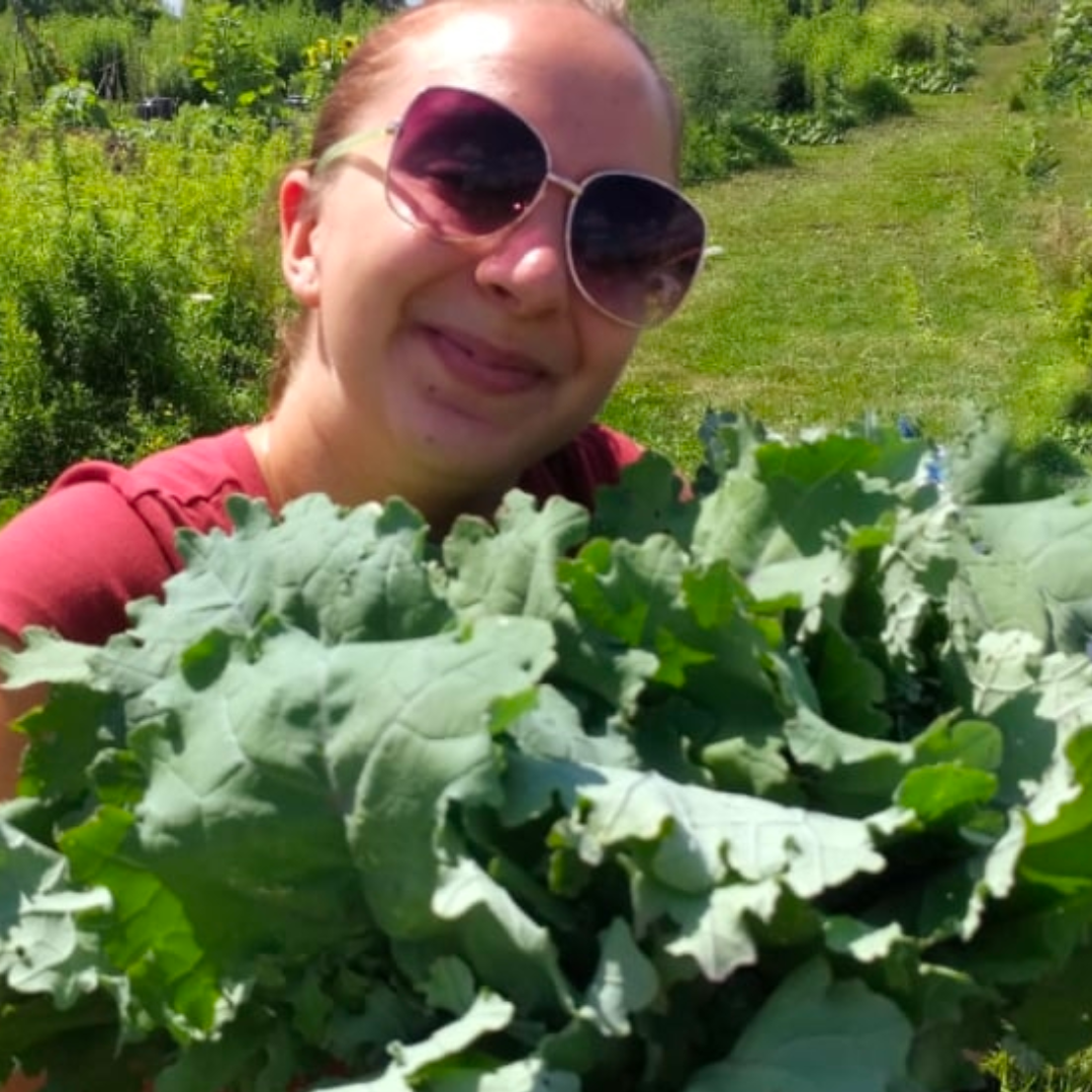 Student holding lettuce outdoors at cambridge food bank 