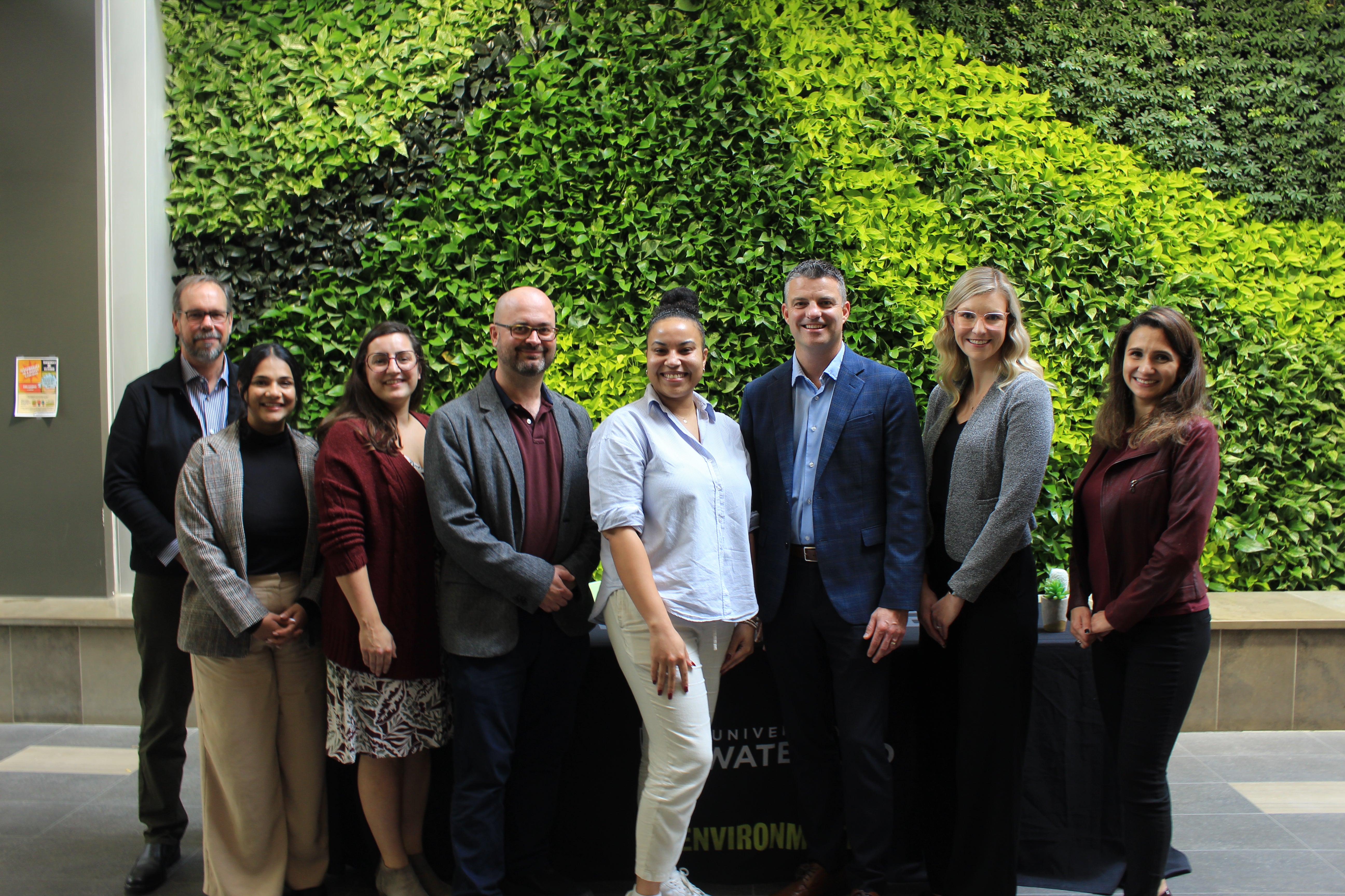 Libro Credit Union, University of Waterloo, and House of Friendship staff pose in front of the Environment 3 green wall