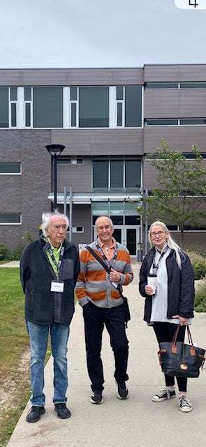 Three individuals standing outside a modern building.