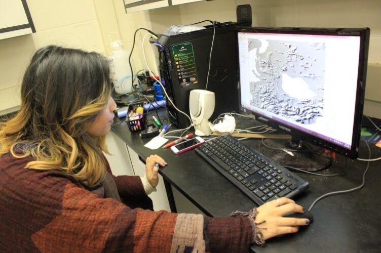 Student sits as computer screen displaying topographical map