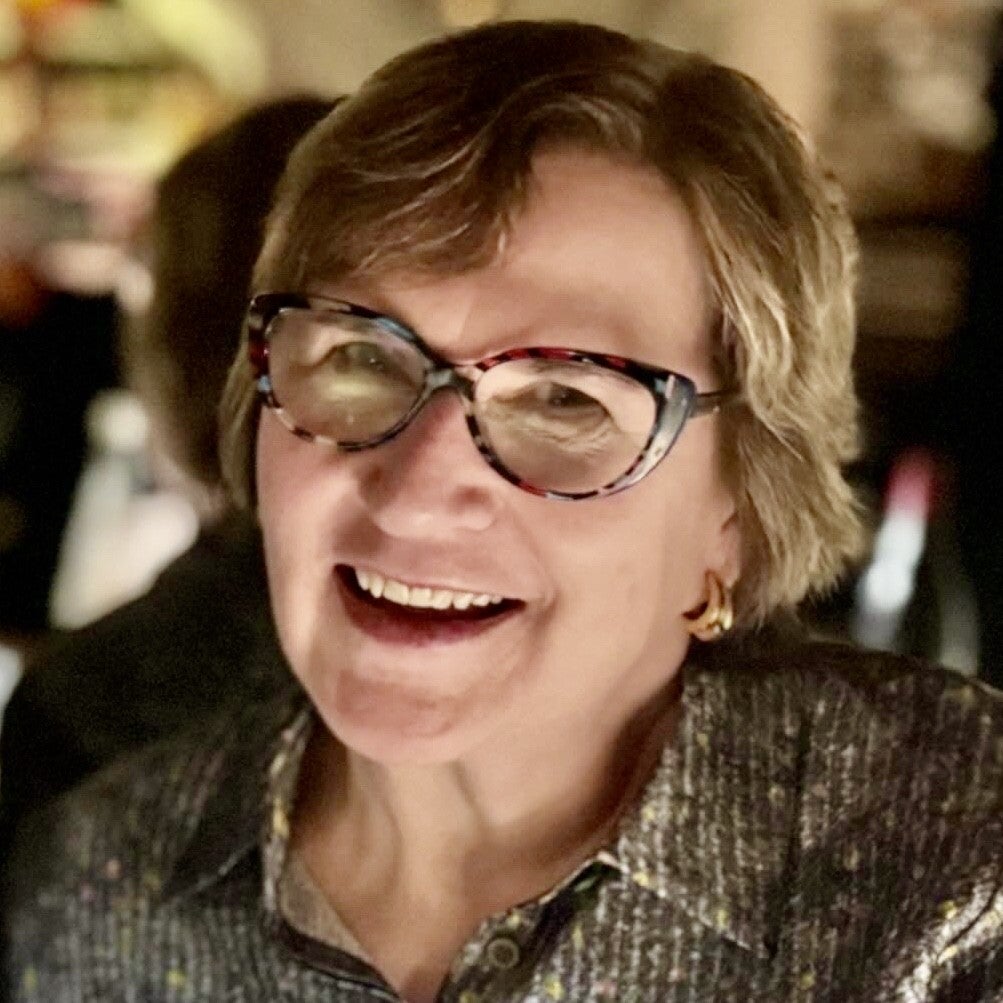woman with glasses and short brown hair smiles.