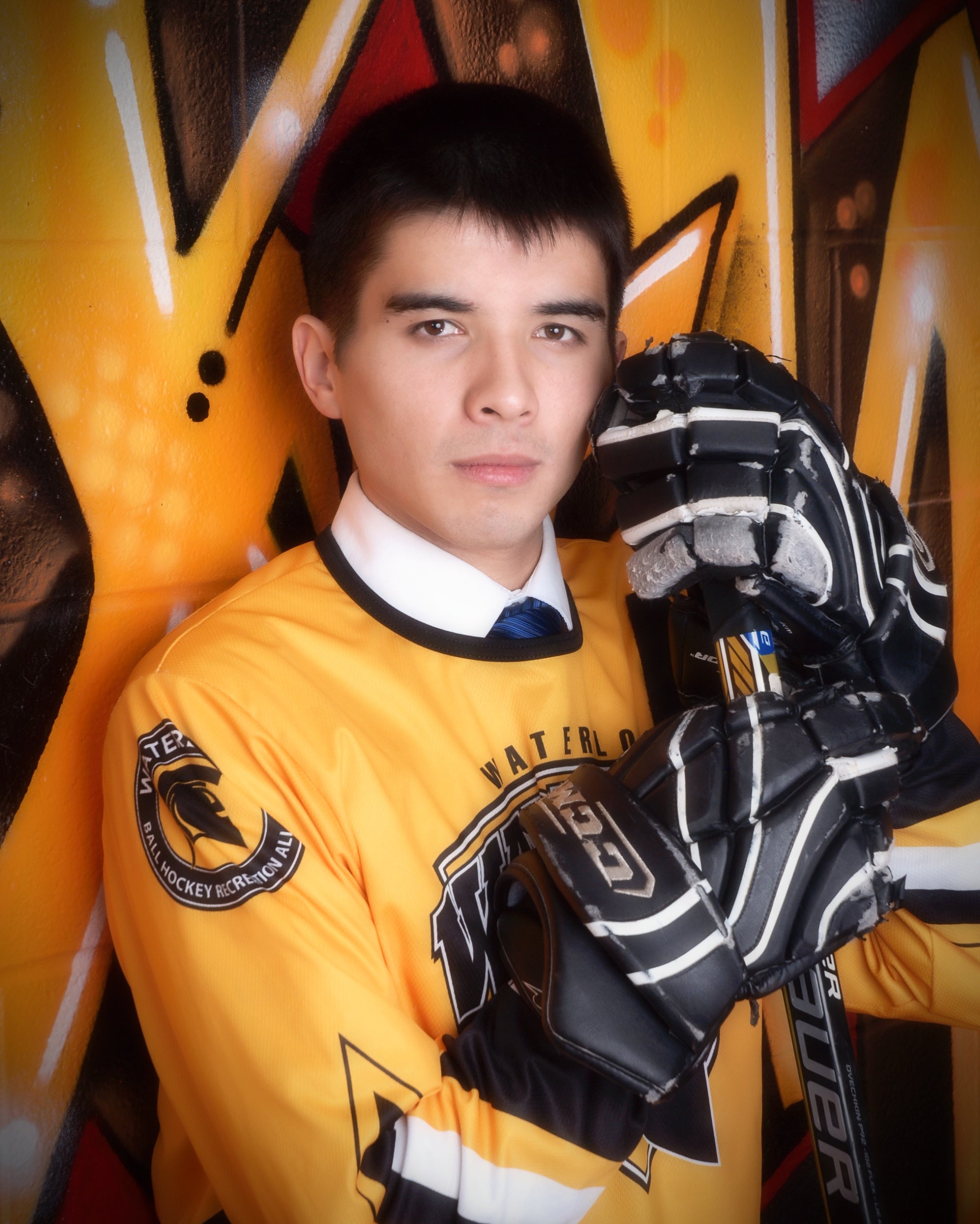 Joseph Wang posing in his University of Waterloo hockey gear and uniform.