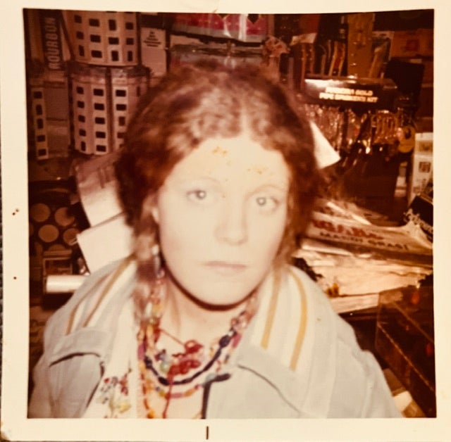 Woman with red braids and layered necklaces in sepia toned photograph.