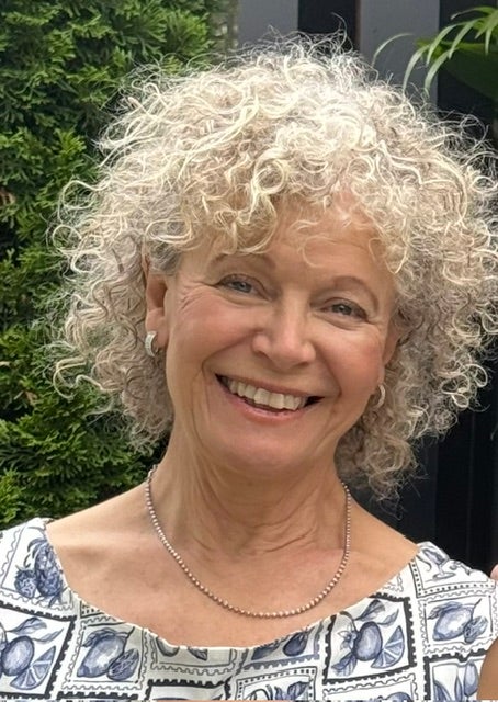 Woman with short, curly blonde hair smiles.