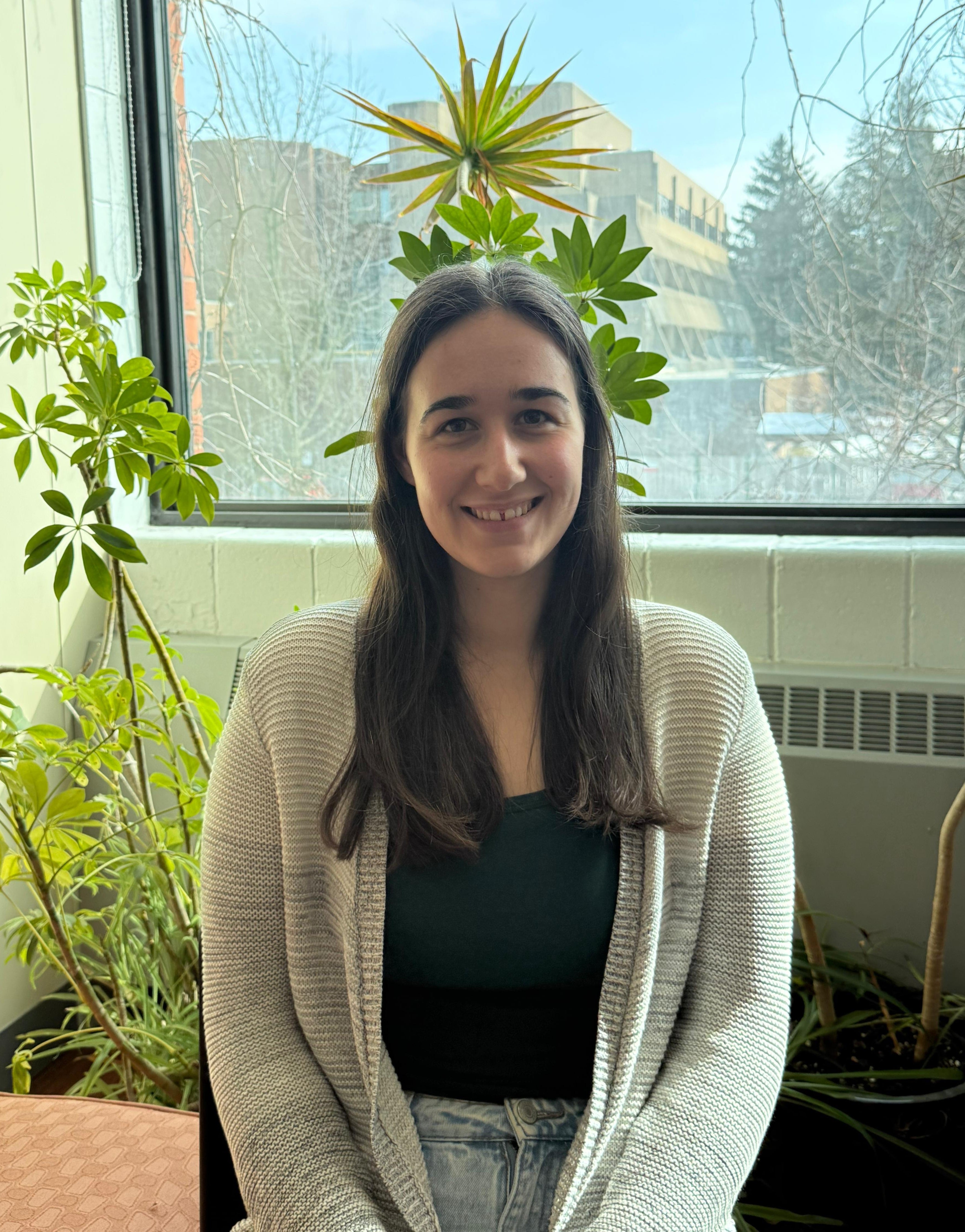 caucasian woman with deep brown hair a white cardigan andd black inner shirt