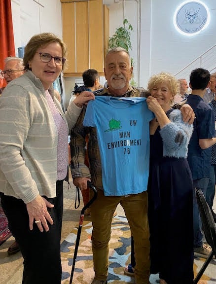 Three classmates from Man-Env '76 holding up a vintage tshirt