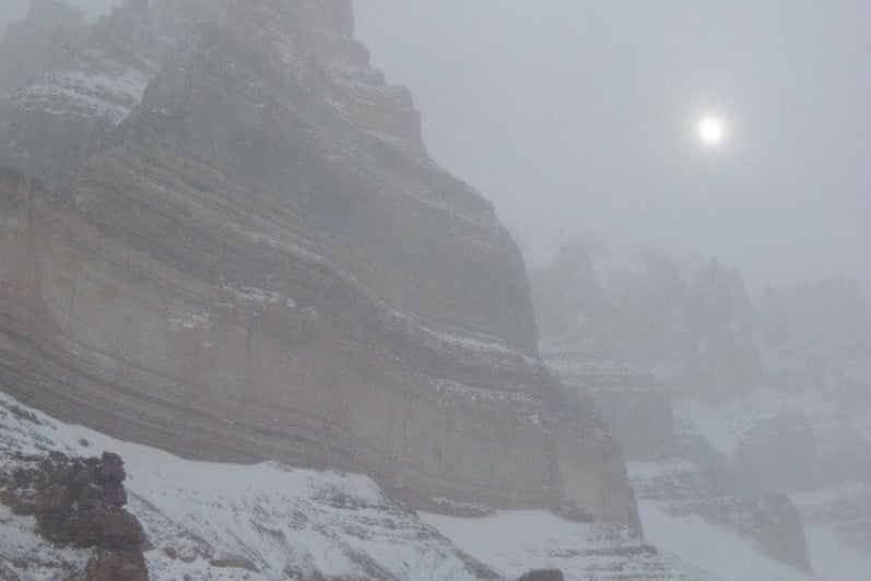Sun behind a cliff on a snowstorm.