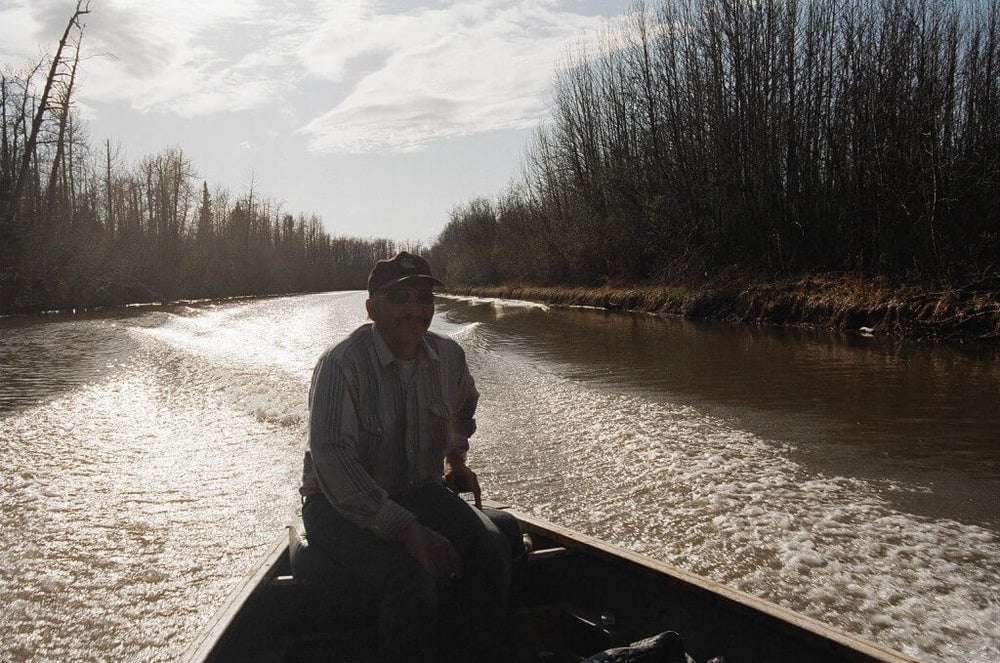 A fisher driving the boat on a river.
