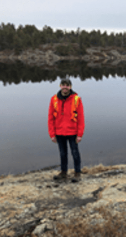 Philip Wright is standing n front of a lake.
