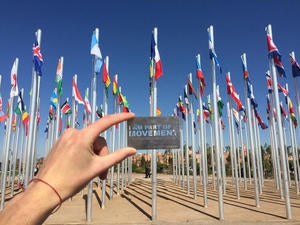 A hand holding up the 'I am Part of Movement' card with flags of countries on the background.
