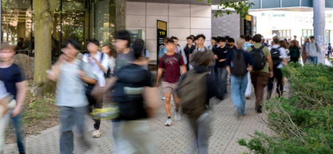 A large group of people walking outside on the University campus