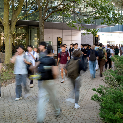 A large group of people walking outside on the University campus