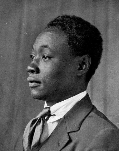 A black and white photo of a black man in a suit with cropped hair posed facing to the left.