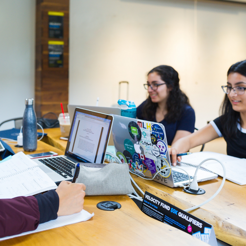 group of 3 students working at a table on their laptops