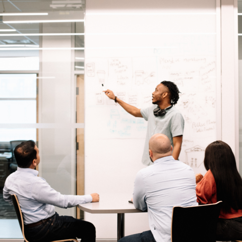 A group of people in a workshop looking at a whiteboard 