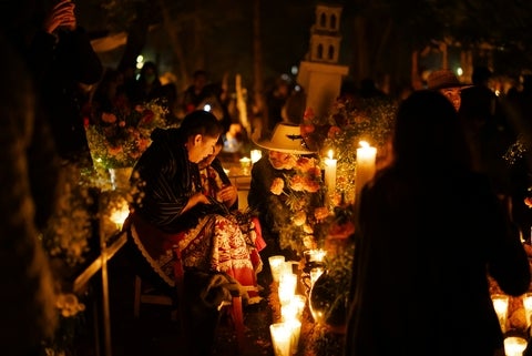 People gathered around a grave with candles and flowers