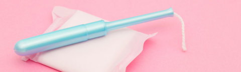 Blue tampon and pad on a pink background