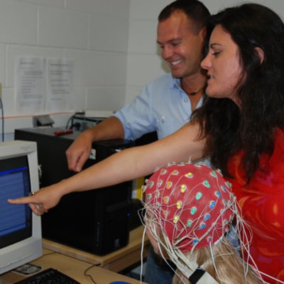 A female lab participant connected with electrodes checking the result on computer screen.